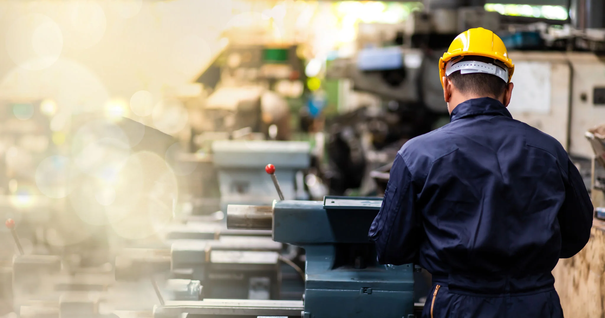 Factory Asian male worker. Asian man Lathe worker in production plant drilling at machine on the factory. Yellow hard hat safety first at mechanic factory.